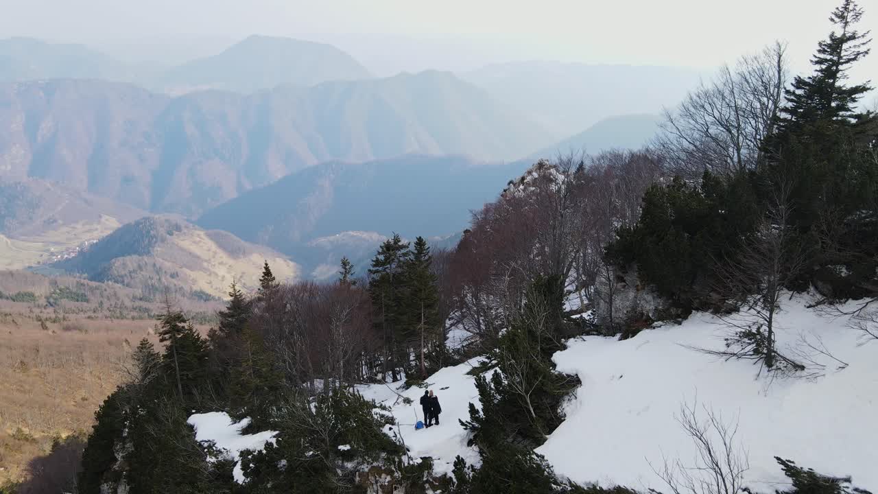 Drone capture hikers on frozen ridge above forested slopes, Grant, Rut, Slovenia