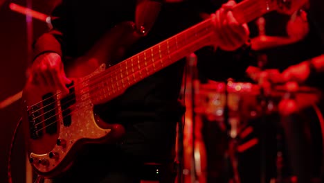 bass guitarist in action in a venue with red lights