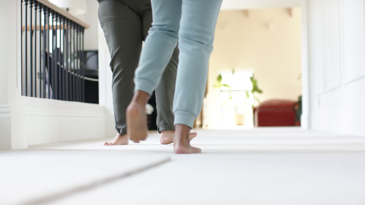 Two bare feet are emerging from doorway on carpeted hall, alternating steps and passing camera