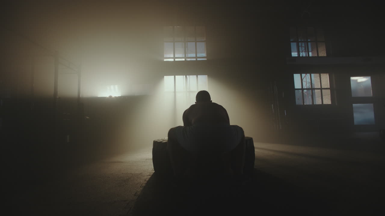 Man Performing Tire Flip Exercise in Gym