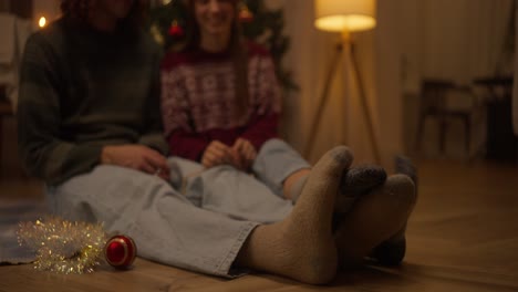 una pareja relajándose junto al árbol de navidad.
