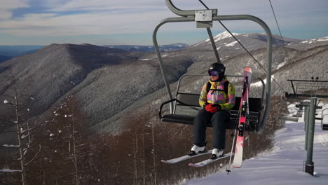 skier on a ski lift with snowy mountains in the background