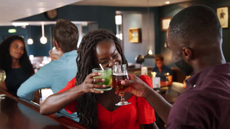 young couple on date meeting for drinks in cocktail bar and making a toast