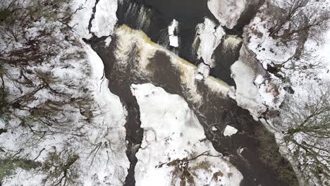 Drohnenaufnahme-Von-Oben-Nach-Unten-Aus-Der-Luft-Eines-Fließenden-Baches-Im-Winter-Mit-Schnee,-Der-Das-Land-Um-Ihn-Herum-Bedeckt