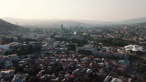 Aerial view of Tbilisi cityscape in Georgia from flying drone at sunset