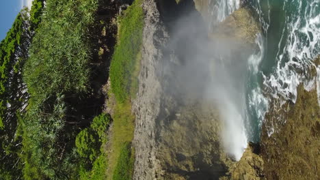 el agua del océano sale de un pequeño agujero en la costa rocosa de la isla de los pinos.