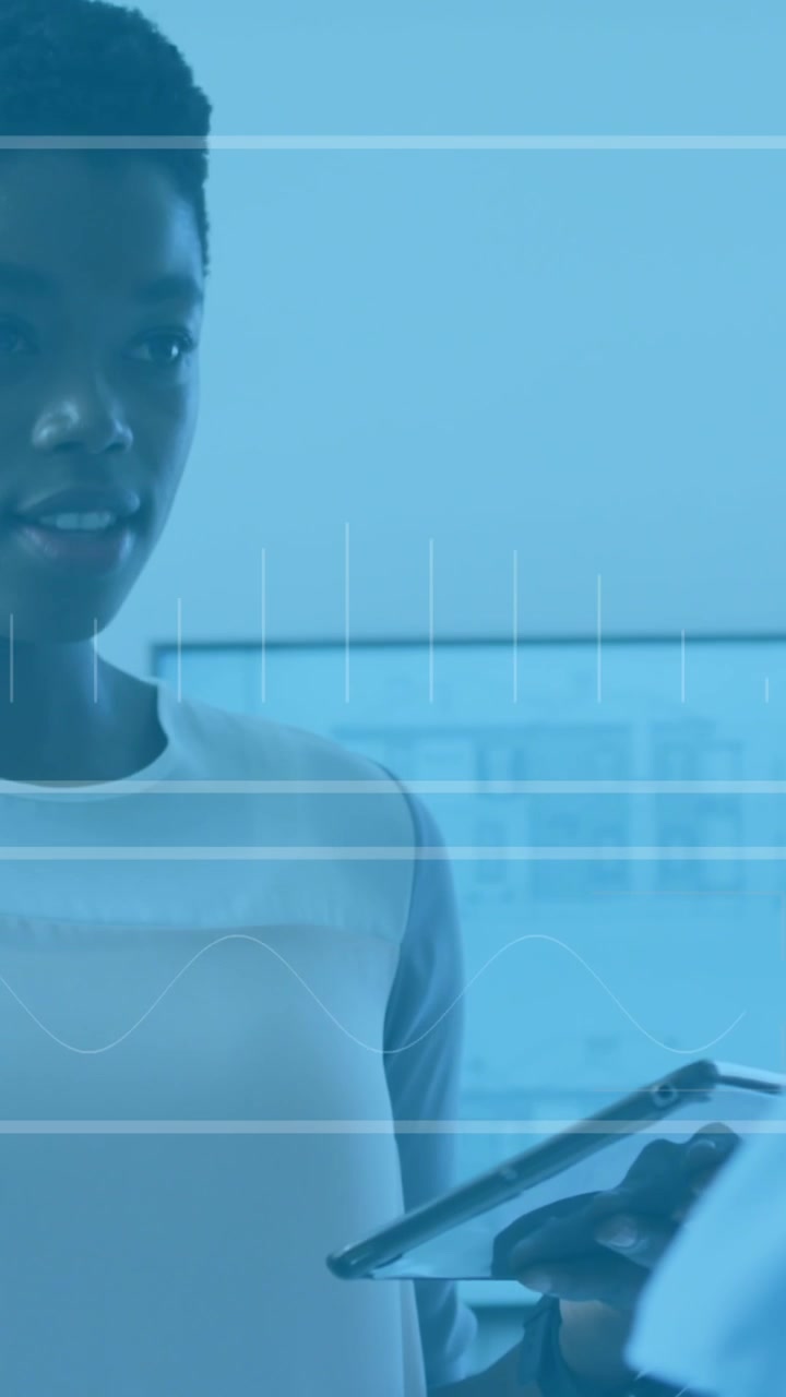Animation of data processing over two diverse women discussing over a digital tablet at office