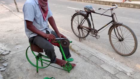 slow cinematic hands of a man sharpening a knife on a diy makeshift sharpening machine on a bicycle frame