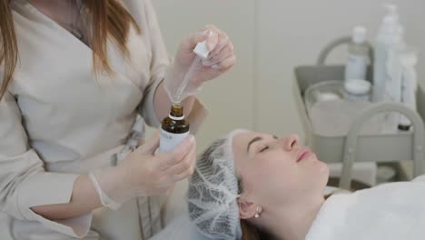 cosmetologist doing face treatment and applying face mask