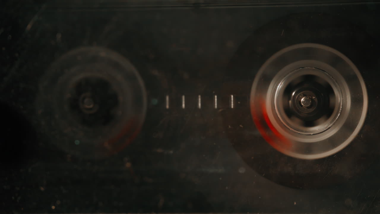 Macro magnetic tape turning steadily inside transparent cassette shell closeup