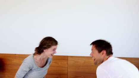 una pareja feliz teniendo una pelea de almohadas
