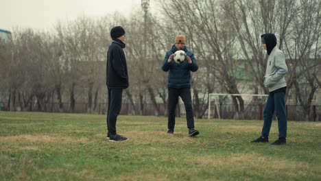 a coach sets the ball in the middle of two players facing each other and blows the whistle, signaling the start of the game, and they played the ball, the background features a goal post, trees