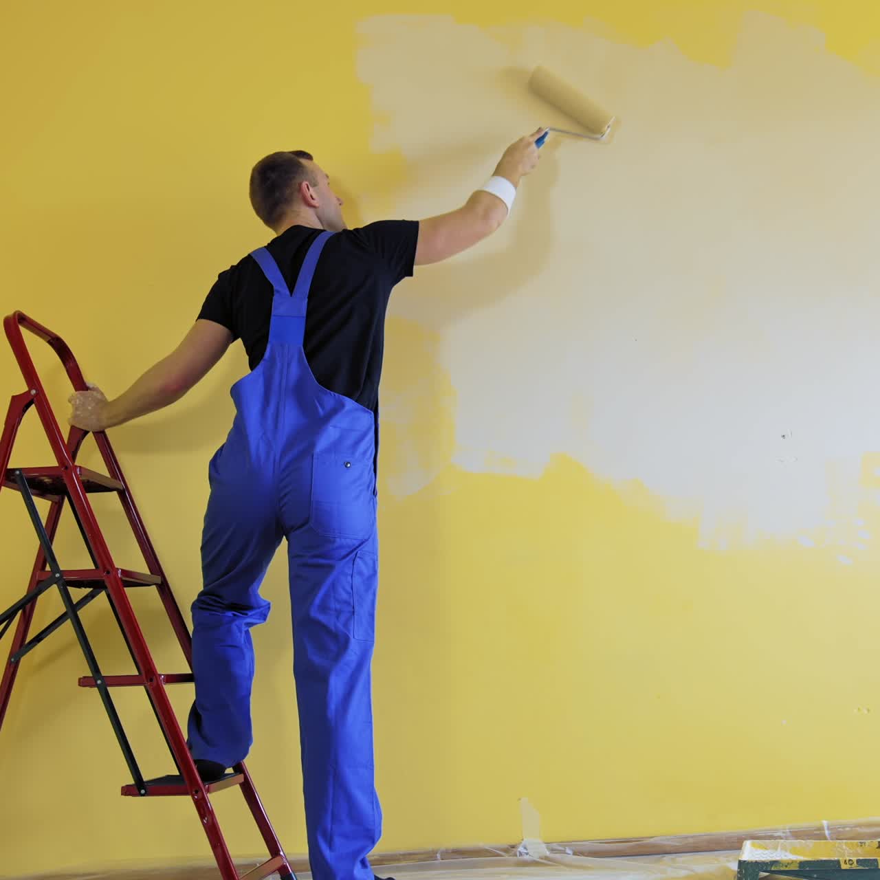 Builder with paint roller. Building contractor painting wall with roller brush