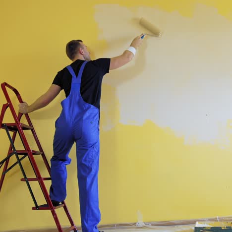 builder with paint roller. building contractor painting wall with roller brush