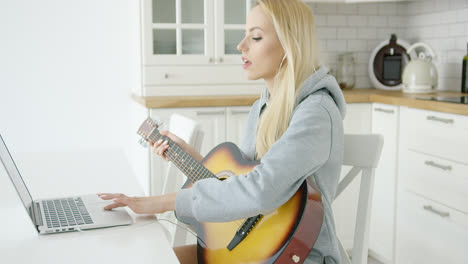 Woman-using-laptop-while-playing-guitar