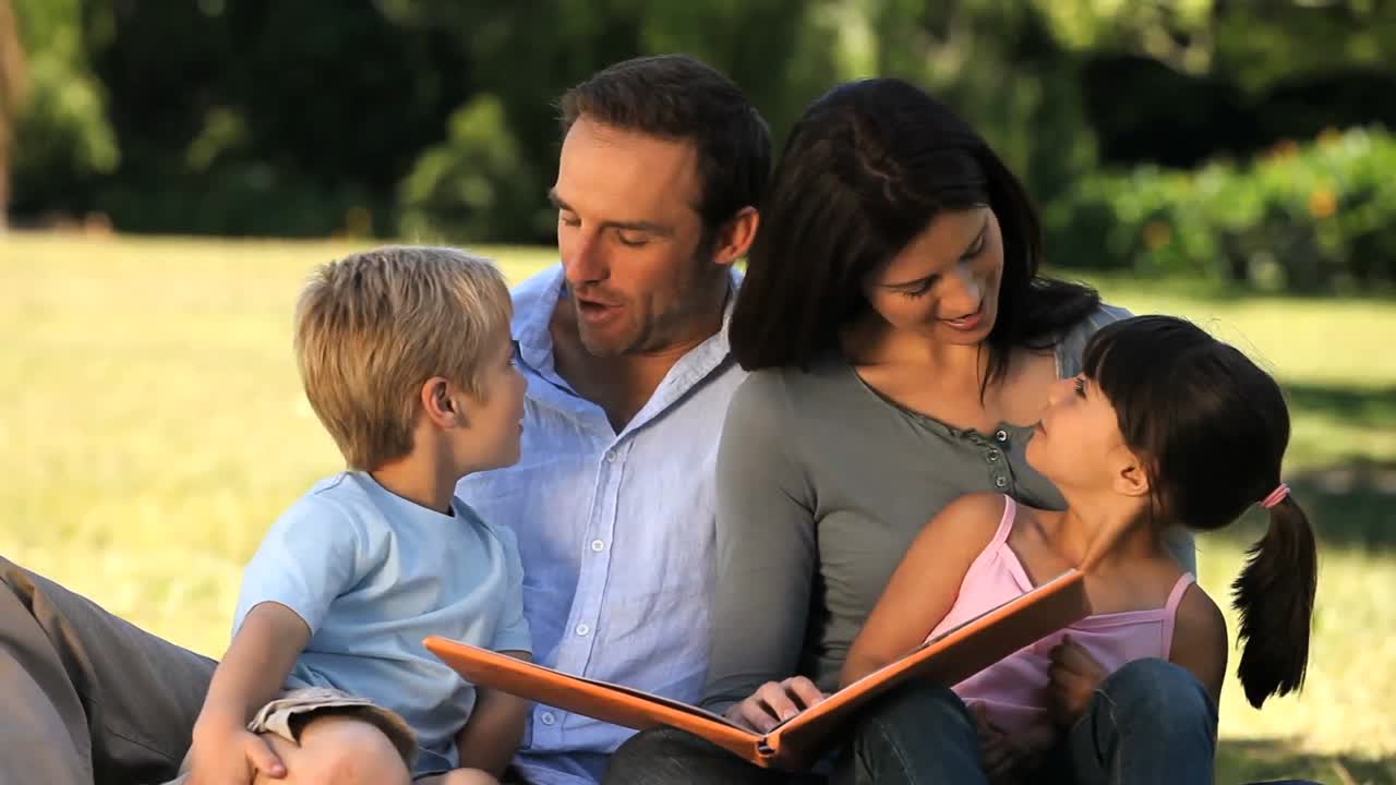 Famiglia che legge un libro seduta sull'erba