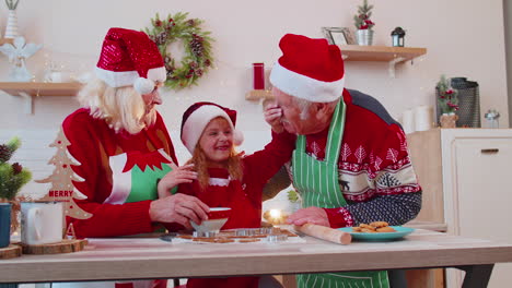 los abuelos mayores y la nieta divertidos jugando con harina en la cara en la cocina de navidad