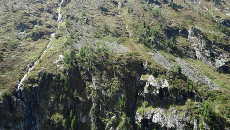 steep mountain slope with waterfall and green vegetation