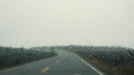 rain landing on the glass of the windscreen as the windscreen wipers move across the screen