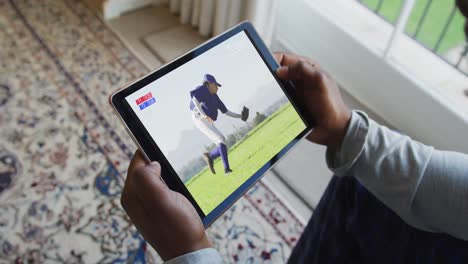 compuesto de un hombre sentado en casa, viendo un juego de béisbol en la tableta