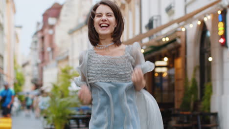 woman jumps in joy on a city street