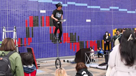 performer throws knives while riding a unicycle.