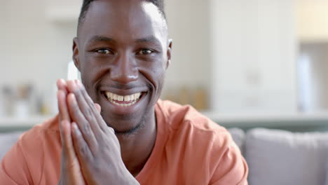 happy african american man sitting and smiling in sunny living room, slow motion