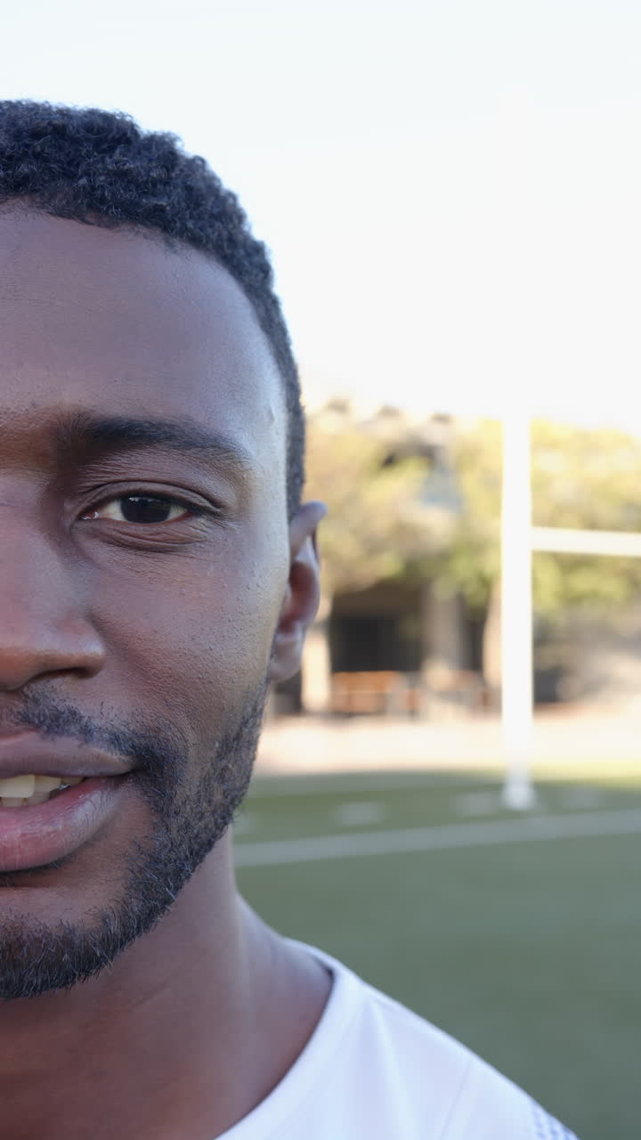 Vertical video: Smiling athlete standing on sports field, enjoying outdoor fitness training