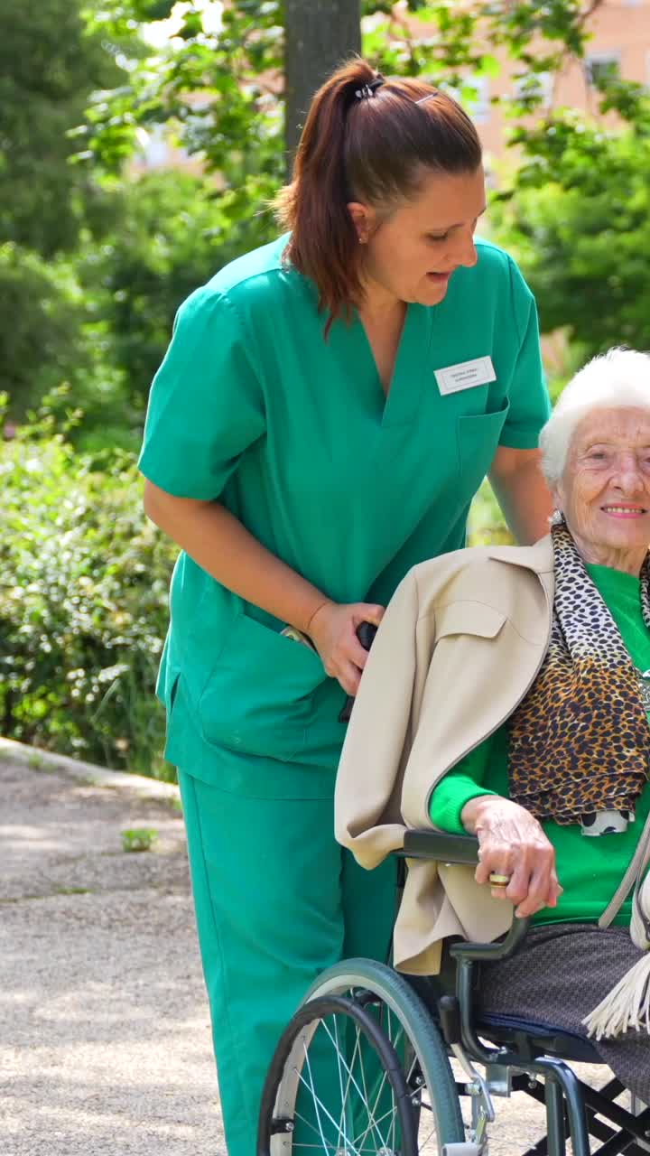 Ältere Frau, die von einer Krankenschwester im Rollstuhl betreut wird