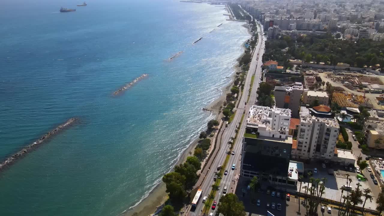 Drone video showcasing a sweeping aerial view of Durrës, Albania, with coastal roads, anchored ships, vibrant urban expansion, and breakwaters under bright daylight, creating a dynamic landscape