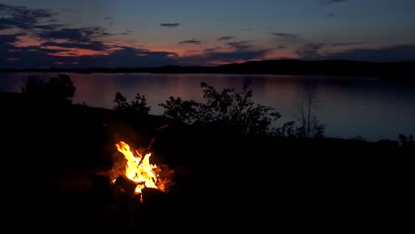 philip edward, island, ontario, canada - the fire catching the gas being thrown in the air by a person in a lakeside - wide shot