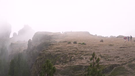 Grupo-De-Senderismo-Ascendiendo-Al-Roque-Nublo-Duroing-Una-Mañana-Brumosa-En-La-Isla-De-Gran-Canaria,-España