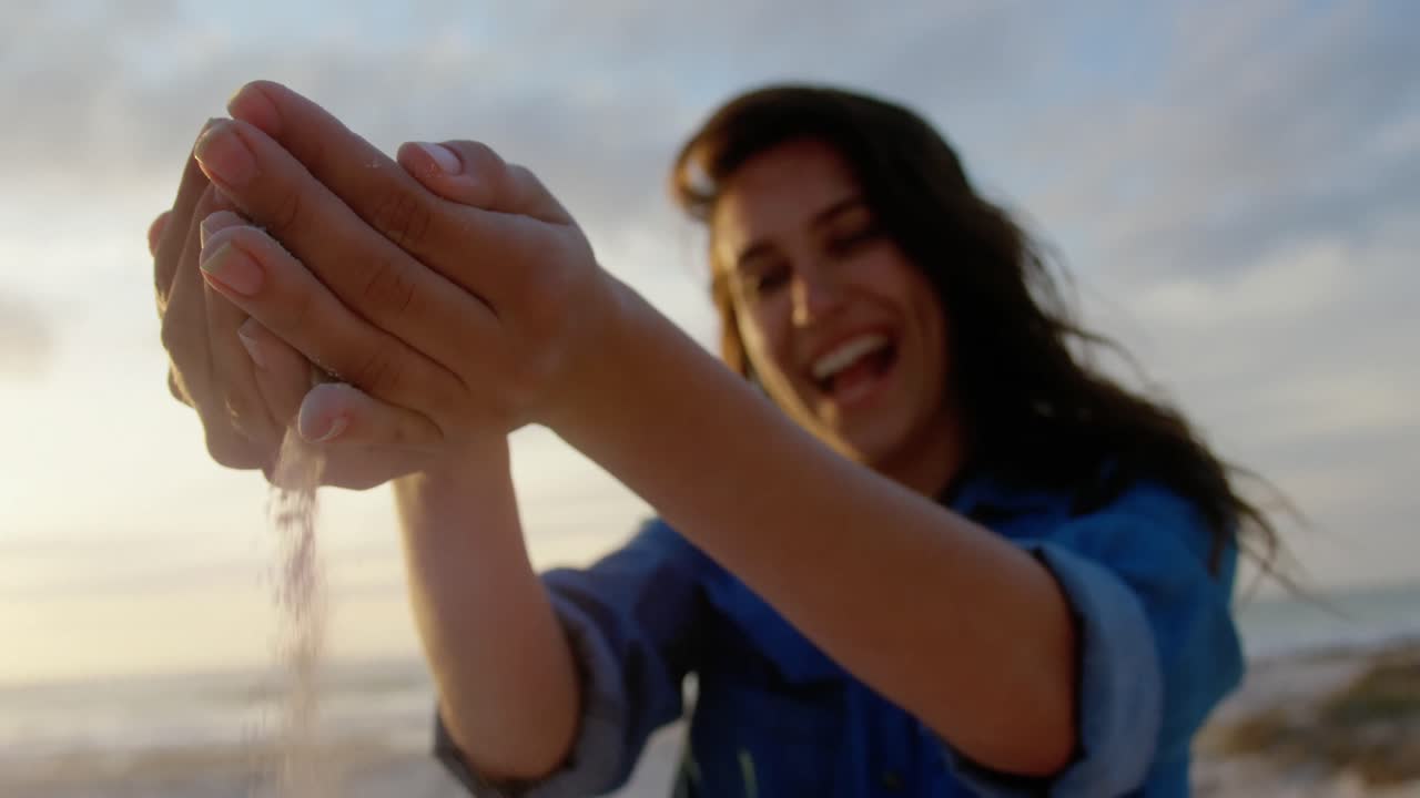 mujer jugando con arena en la playa 4k