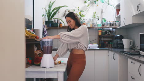 una mujer joven usando una licuadora para hacer un batido