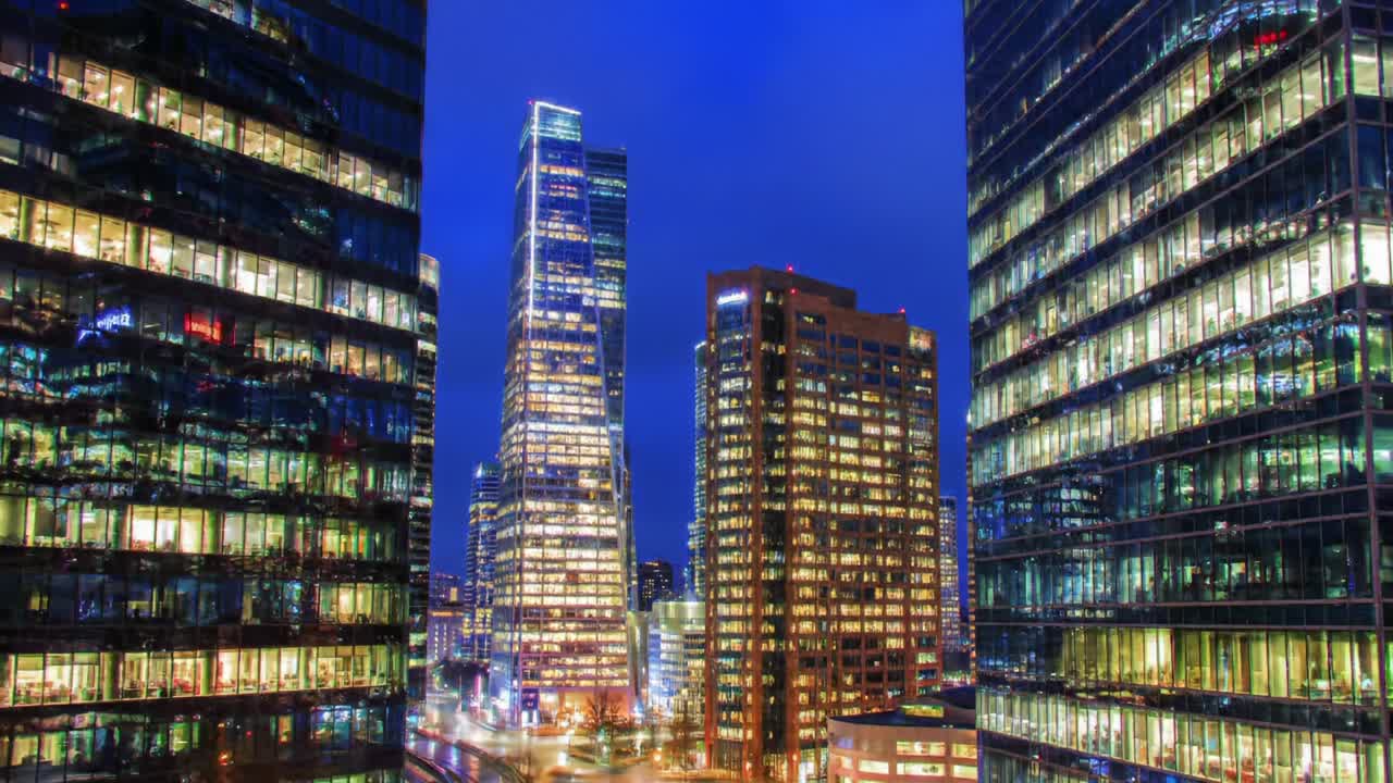 Nighttime Cityscape: A Captivating View of Modern Skyscrapers Illuminated by Neon Lights Against a Darkening Sky, Showcasing Urban Architecture and Vibrant Life