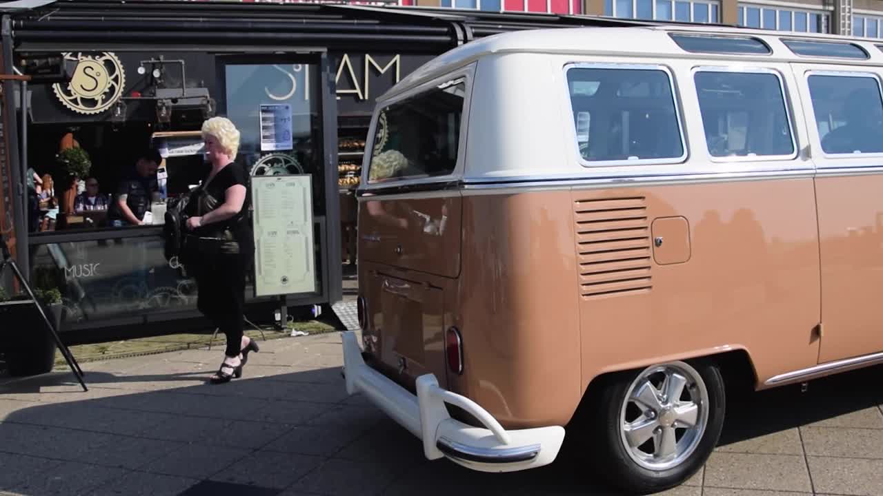 Vintage VW camper driving in front of restaurants and cafes on the Scheveningen boulevard by the North Sea