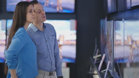 couple in shopping. they are looking for new tv. they are pointing fingers at tv. shallow depth of field. 4k uhd