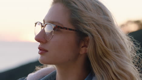 Retrato-De-Una-Mujer-Feliz-Contemplando-El-Futuro-Disfrutando-De-Un-Estilo-De-Vida-Despreocupado-Sintiéndose-Positivo-Relajándose-Mirando-El-Atardecer-Junto-Al-Mar-Con-Gafas