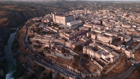 an upward drone shot of toledo, its alcazar and its cathedral at sunrise