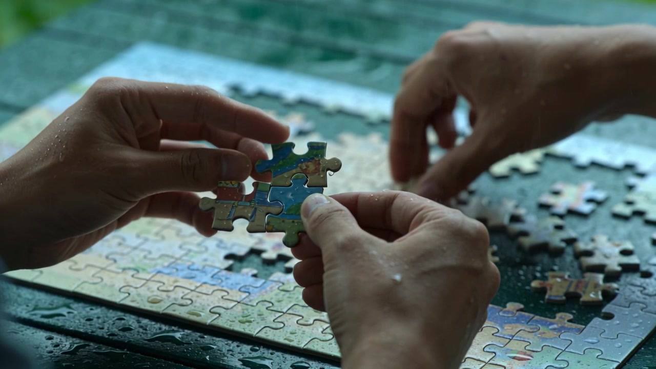 Trazendo a terceira peça, duas mãos unindo um grupo de quatro peças de quebra-cabeça na janela, montando o quebra-cabeça.