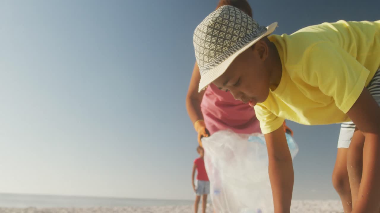 Pareja afroamericana mayor con sus nietos clasificando residuos en una playa soleada