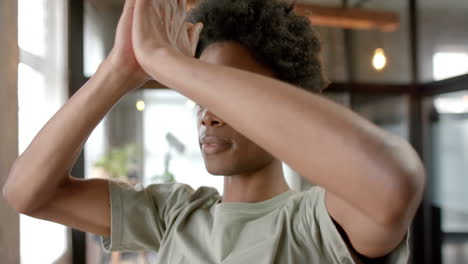 African-american-man-doing-yoga-and-meditating-at-home,-slow-motion