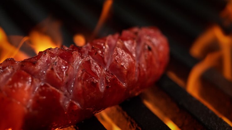 Fire Roasted Sausage Barbecuing On A Grill Grate Among Bursting Flames, BBQ in Macro and Slow Motion