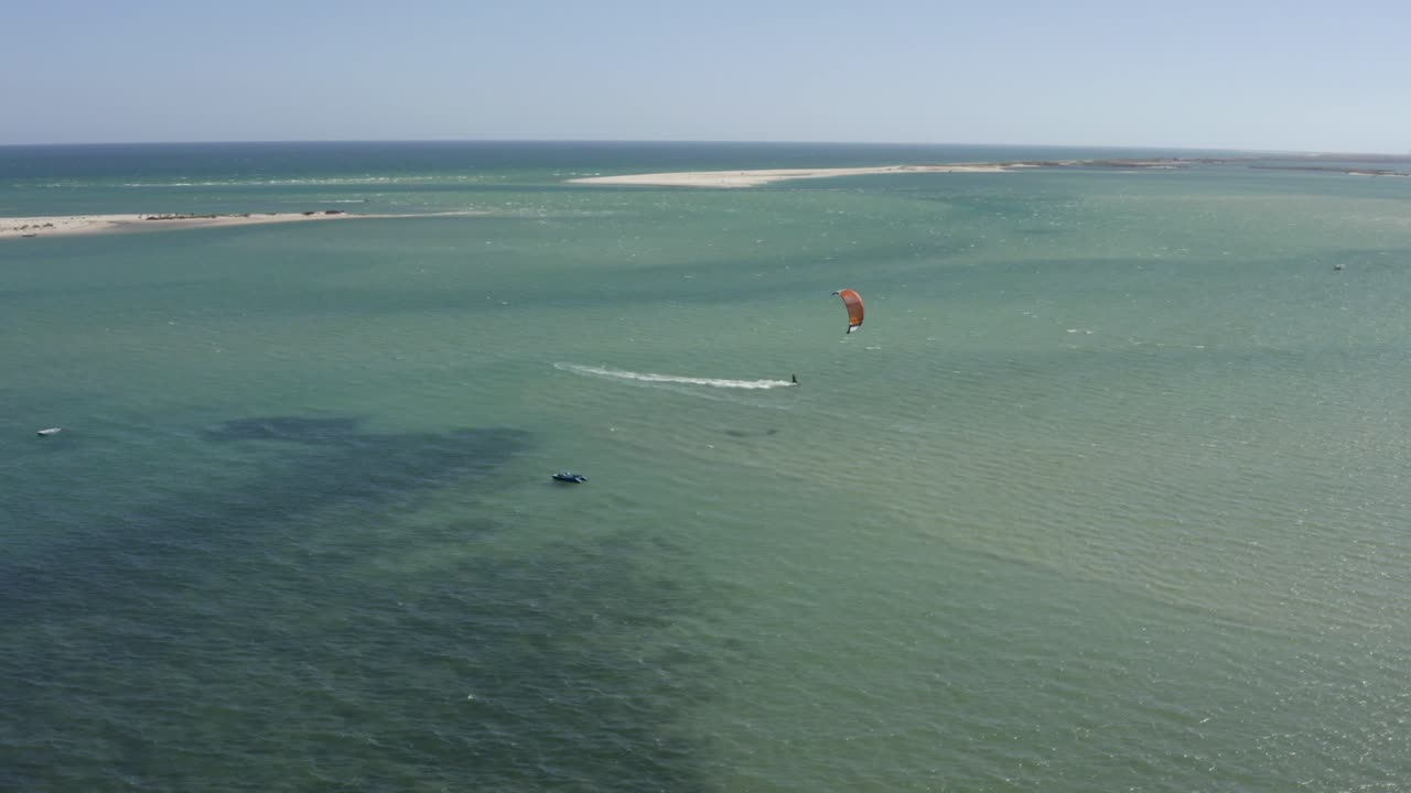 drone orbita alrededor de un windsurfista de kite atlético tallando el océano en fuzeta portugal, antena