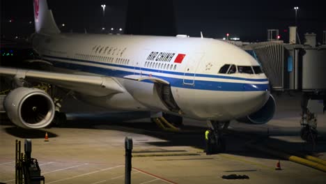 at night, an air china jet is stationed on a runway at beijing international airport, illuminated by runway lights.
