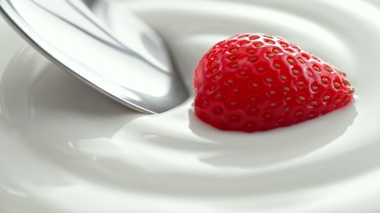 fresa recogida con cuchara de plata de yogur espeso y cremoso en macro y cámara lenta