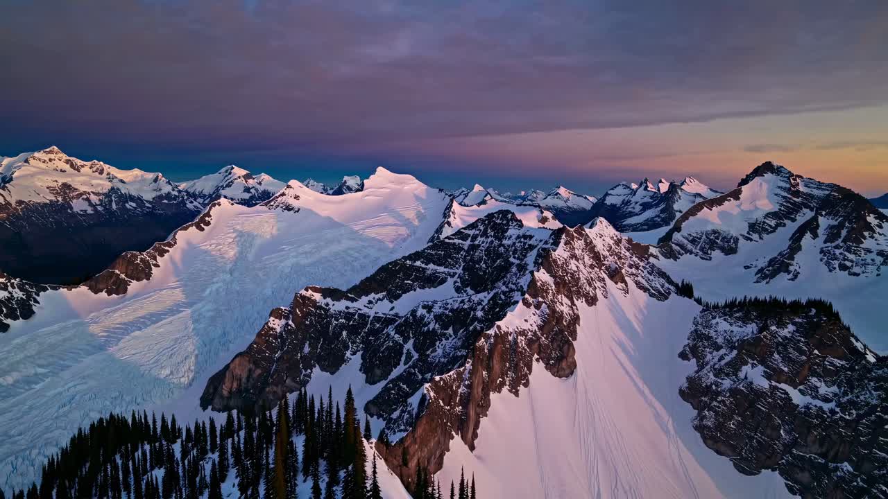 Aerial video capturing majestic snow-capped mountains at sunset, with sweeping panoramic views