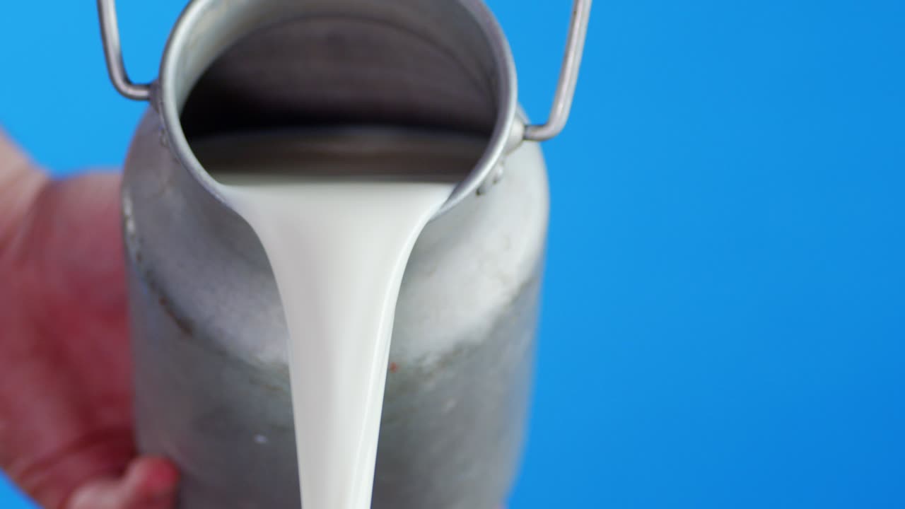 남자의 손은 통에서 신선한 우유를 부었습니다.