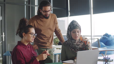 diverse coworkers discussing project on laptop