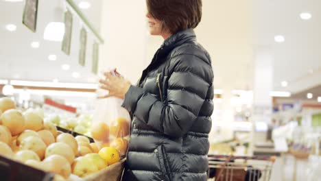 young woman shopping in grocery chosing oranges